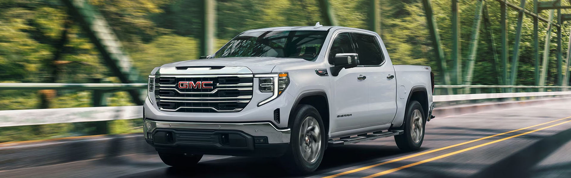 2026 GMC Sierra 1500 white pickup truck crossing a countryside bridge