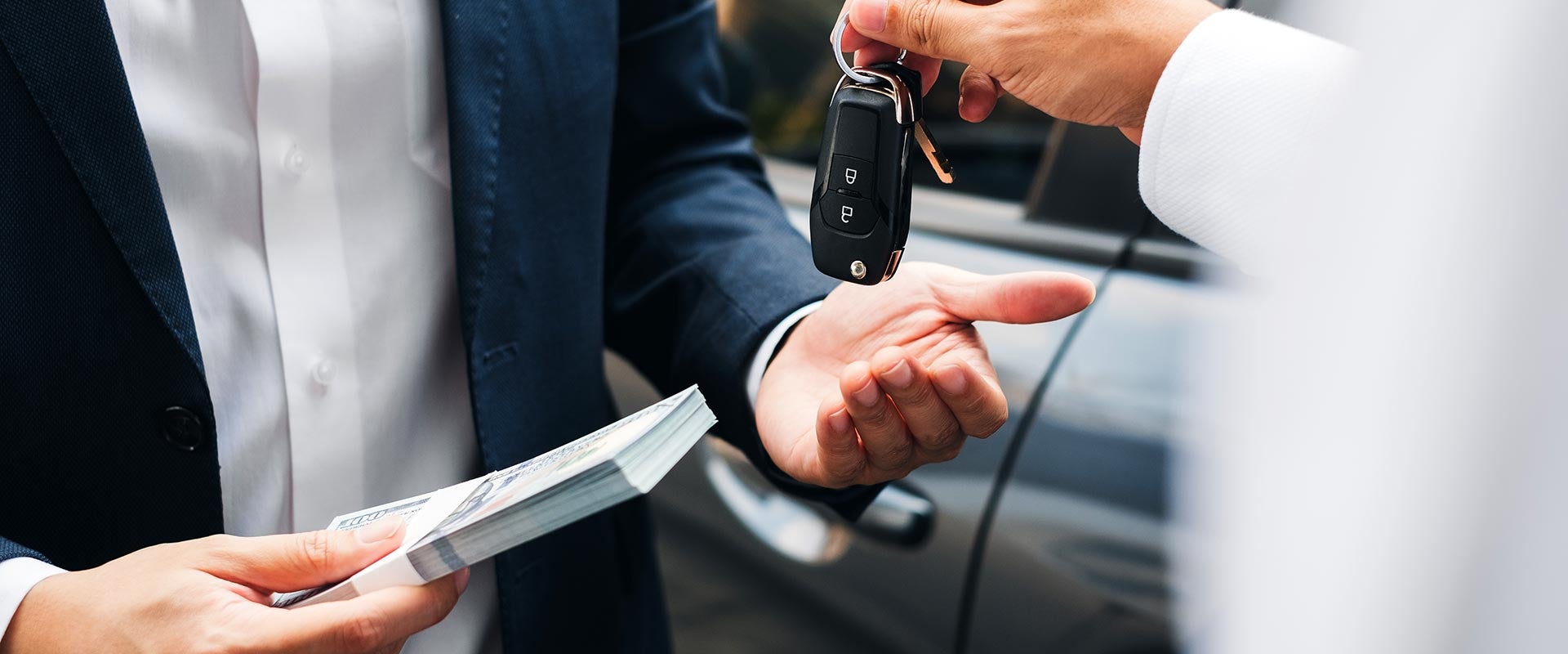 Man receiving keys as he gives cash for his new GMC SUV